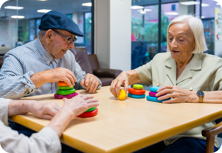 Elderly people playing with colorful stacking toys.