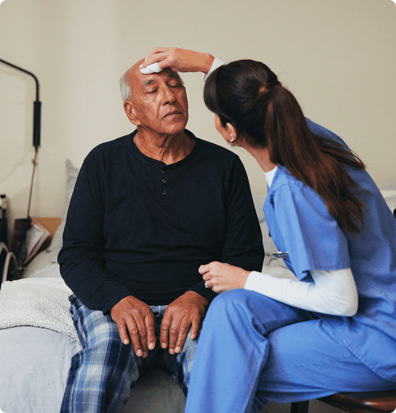 GettyImages-2201047239 Nurse tending to elderly man's forehead.
