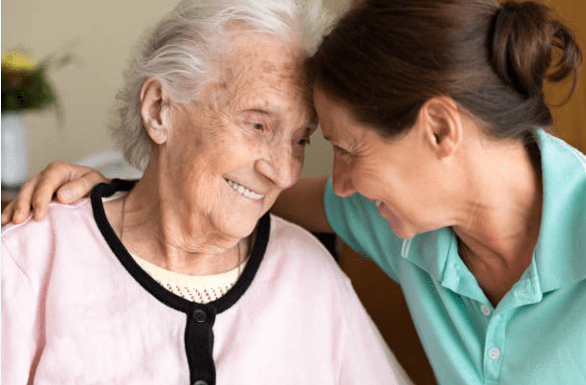 Elderly woman and caregiver sharing a smile.